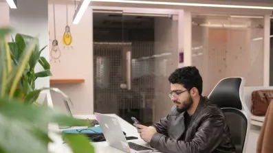 Associate checking phone at laptop in office