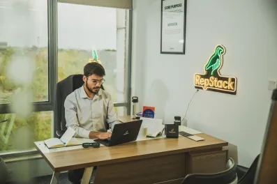 Man working at desk near RepStack neon sign, illustrating past offshore hiring failure.
