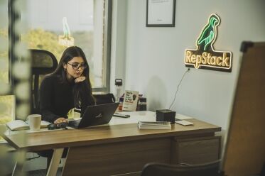 Associate working at desk with RepStack neon sign.