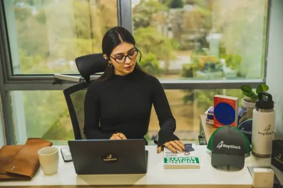 RepStack associate working at desk with laptop and cap