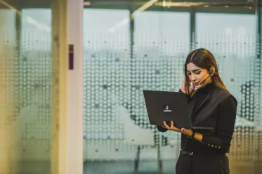Associate reviewing branded laptop while standing.