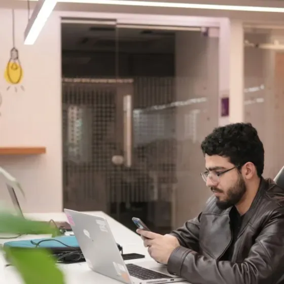 Associate checking phone at laptop in office